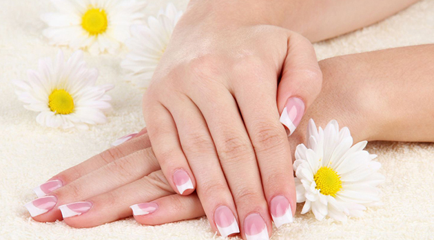 Woman hands with french manicure and flowers on towel