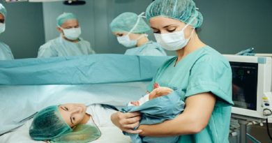 Operating room nurse showing newborn to mother