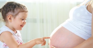 Little cute girl looking at her mother pregnant tummy